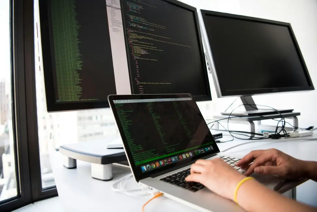 Arbeit am Notebook vor zwei Monitoren